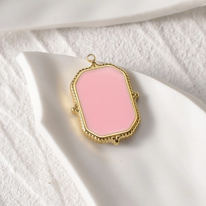 Detailed macro view of a 14k gold-plated rectangular charm with pink enamel inlay