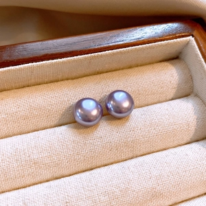 Macro shot of elegant purple pearls in a beige fabric-lined wooden jewelry box