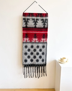 Detailed close-up of thick winter scarf with geometric patterns and red fringe accents