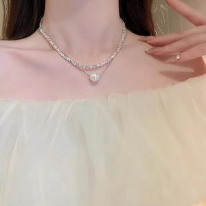 Detail of double-layered necklace featuring silver textured chain and round pearl pendant