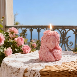 Pink 3D floral girl scented candle shaped like a sleeping girl with flowers on a lace table