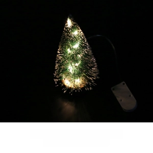Close-up of a mini green cedar Christmas tree with warm LED lights and snowy tips