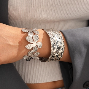 Bracciale rigido argento minimalista con fiore a pieghe e trama martellata indossato da modella