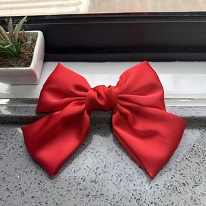Detailed view of the red satin fabric texture on a large elegant bow hair clip