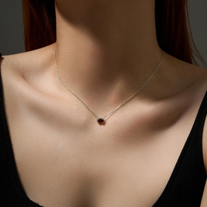 Close-up of elegant S925 silver necklace with a red oval gemstone on a female model
