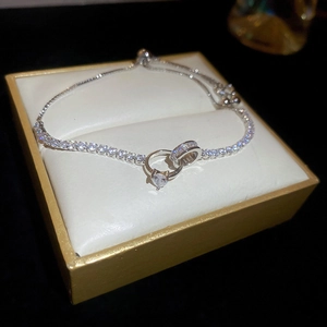 Close-up of zircon knot bracelet with heart pendant in a premium jewelry gift box