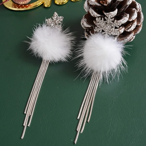 Close-up of snowflake crystal earrings with white fur balls and silver tassel chains