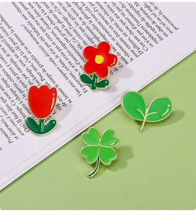 Détail macro de broches en émail représentant une tulipe rouge et un trèfle vert