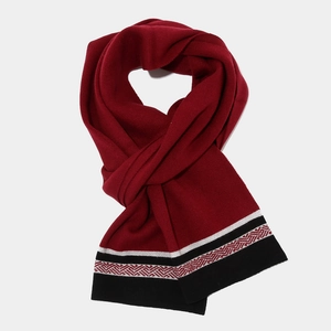 Detail view of burgundy knitted scarf with ethnic geometric patterns and striped edges