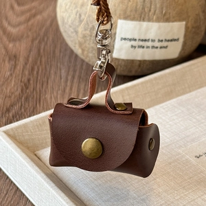 Close-up of vintage dark brown leather mini pouch with bronze metal hardware and snap button