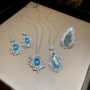 Detailed view of silver jewelry set with blue teardrop stones, pearls and zircon accents