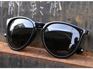 Detail of vintage black cat-eye polarized sunglasses on a rustic metal surface