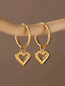 Detailed view of gold heart dangle earrings on a wooden stand with a warm background