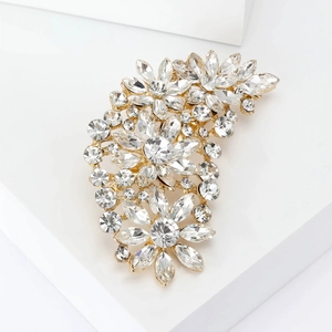 Close-up of golden floral brooch with sparkling clear crystals and intricate metal details