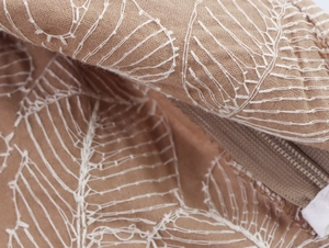 Close-up of white leaf embroidery on light brown cotton linen fabric with hidden zipper