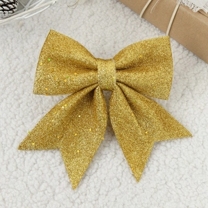 Glittering gold Christmas bow ornament on white faux fur background for tree decoration