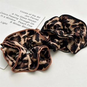 Detail of leopard print scrunchies with fine stitching and ruffled texture on white