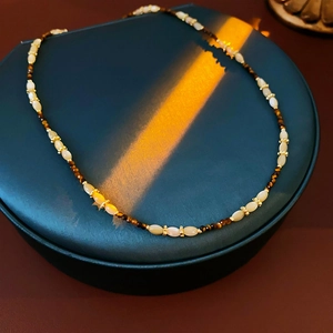 Détail macro du collier en nacre florale avec perles marrons sur un étui à bijoux