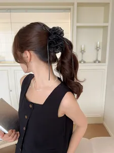 Detail of a black tulle scrunchie with ribbons tied on a ponytail for a fluffy look