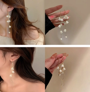 Detail showing white flower petals, pearls and long gold tassels on elegant earrings