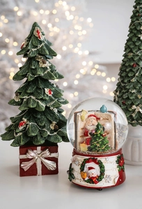 Close-up of resin Christmas tree and Santa snow globe with festive holiday lights