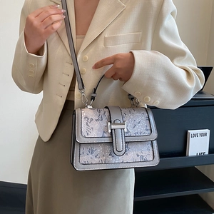 Detail of grey crossbody bag featuring floral embossed texture and silver metal buckle