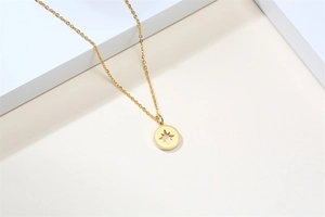 Detailed view of a gold octagonal star pendant on a minimalist stainless steel chain