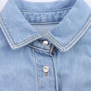 Detailopname van kraagnaden en zilveren metalen knoop op het lichtblauwe denim vestje