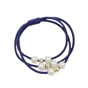 Élastique à cheveux bleu marine avec perles blanches et billes dorées sur fond blanc