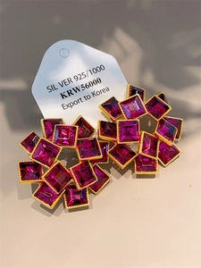 Detail of red gemstone cluster earrings on white card showing gold metal backings