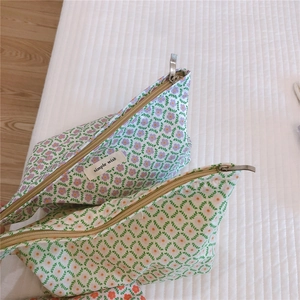 Close-up of floral cotton pouches with zipper and 'simple wish' label on quilted bed