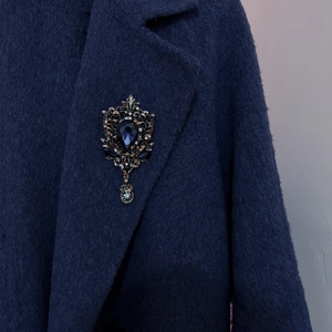 Vintage water drop brooch with dark blue gemstone on navy blue wool coat lapel