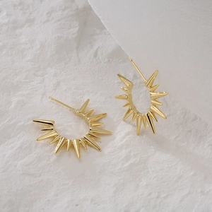 Golden spiked starburst earrings with 18K gold plating on textured white background