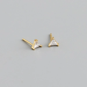 Macro detail of triangle cut zircon stud earrings with minimalist gold claw setting
