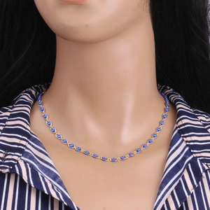 Detailed view of evil eye charm on golden chain necklace worn on the neck