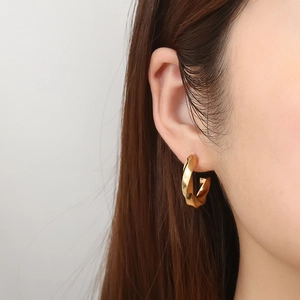 Polished 18K gold plated stainless steel twisted C-shape hoop earrings on model