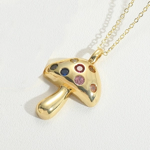 Macro detail of gold mushroom pendant necklace with colorful inlaid zircon gemstones