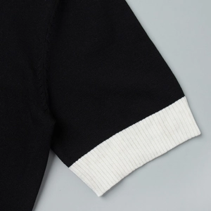 Détail du revers côtelé contrasté sur ce haut polo en maille à manches courtes noir
