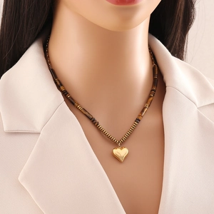 Tiger eye beaded necklace with a golden heart pendant worn on a model's neck