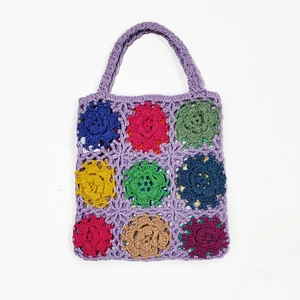 Detailed close-up of colorful handmade crochet floral patterns on a purple knitted handbag