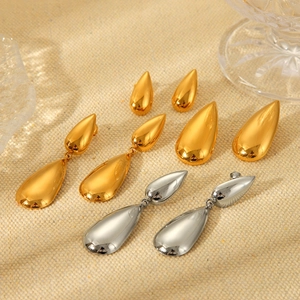 Polished stainless steel water drop earrings in gold and silver finish on textured fabric