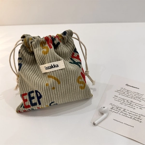 Detail of sage green corduroy drawstring pouch with retro colorful letter print