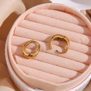 Close-up of golden teardrop hoop earrings displayed on pink velvet jewelry box padding