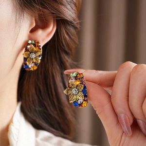 Close-up of vintage court style flower earrings with colorful gems and pearls