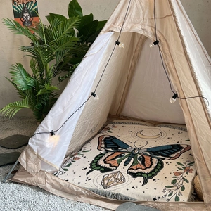 Detail of bohemian woven blanket featuring butterfly and moon patterns with fringe