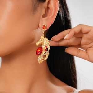 Close-up of vintage golden horse head earring with red crystal and sparkling rhinestones