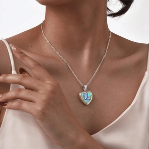 Detailed close-up of heart-shaped iridescent abalone shell locket on a gold necklace