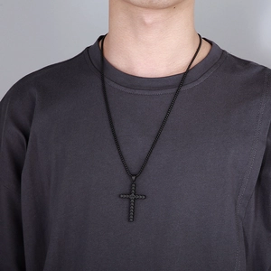 Close-up of black stainless steel cross necklace with wheat pattern on model