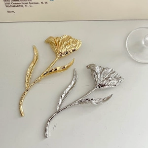 Detailed view of tulip-shaped metal brooches in gold and silver finish with fine texture