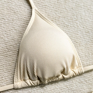 Macro detail of beige ribbed fabric on triangle bikini top with drawstring texture